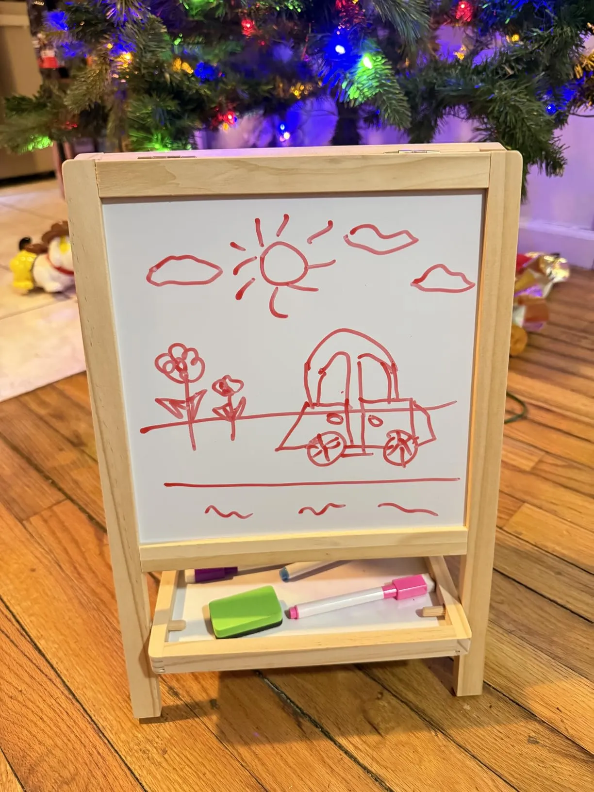 Detailed sun and car drawing on whiteboard under Christmas tree