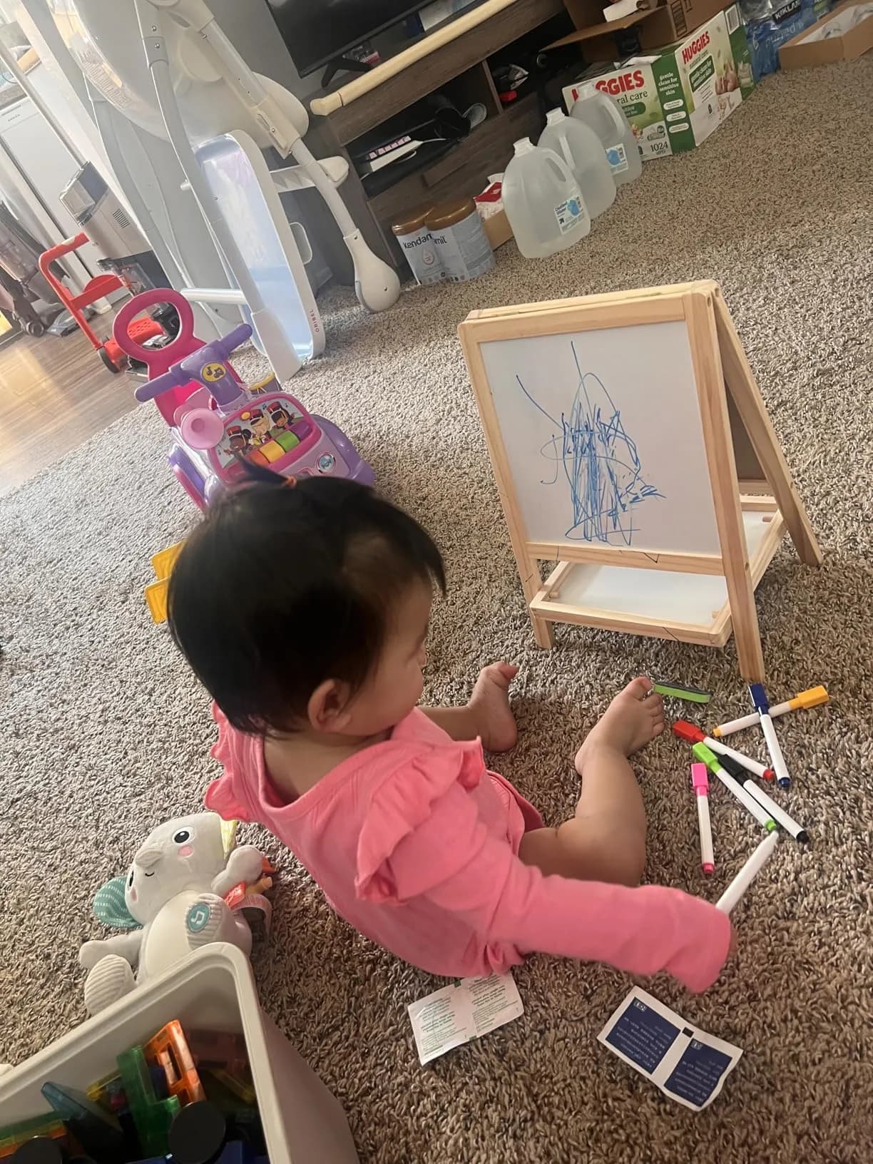 Baby girl in pink drawing on the whiteboard